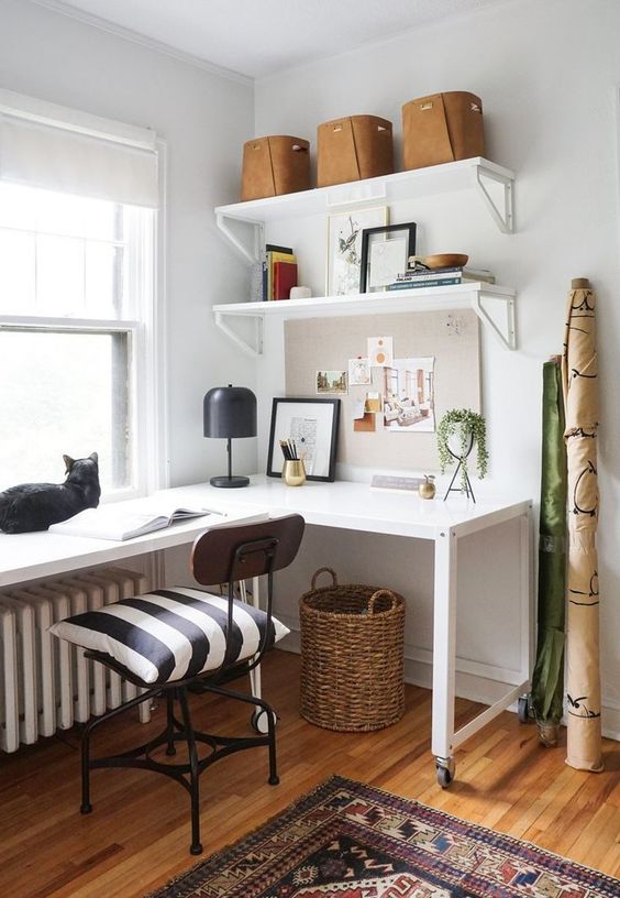 A stylish mid century modern home office with a white corner desk, a black industrial chair and open shelves is chic