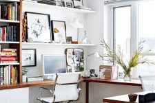 a stylish modern home office nook in white, with a corner desk and a bookcase on one side and a gallery wall on shelves