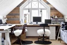 an attic farmhouse home office with a reclaimed wood accent wall, a large L-shaped desk, mismatching chairs, pendant bulbs and storage units