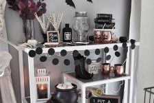an elegant Halloween bar cart with black and white pumpkins, black dot garlands, copper mugs, bats and dark leaves