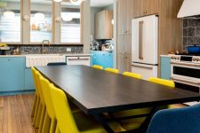 02 The eat-in kitchen shows off blue and white cabinets, a wooden dining table and yellow and navy chairs