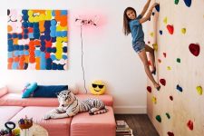 03 a colorful kids’ playroom with a climbing wall, pink sofas, colorful artworks and a rug plus toys