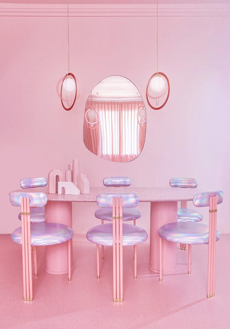 The dining room is done with a pink oval table, iridescent chairs and pendant lamps plus an oddly shaped mirror