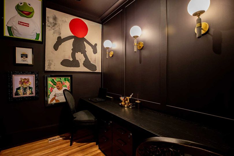 The home office is all dark, with a shared desk, a couple of black chairs and a bright gallery wall