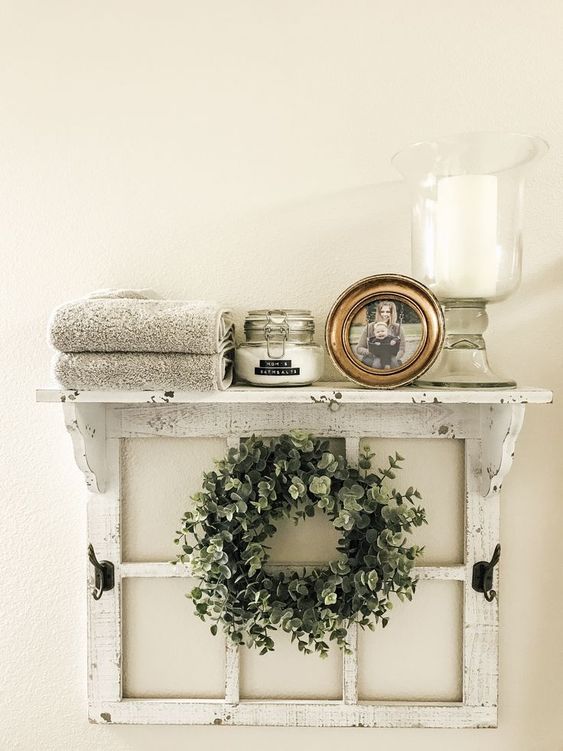 a cool and easy shelf of an old window frame, with a greenery wreath, a candle, a photo, some blankets is ideal for a bathroom