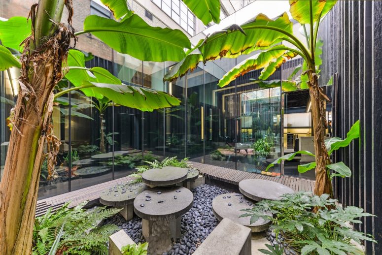 An inner courtyard is like a garden, with tropical trees, pebbles and some stone furniture