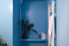 07 The bathroom is done in light and power blue, with a zoy shower nook and some bright tiles