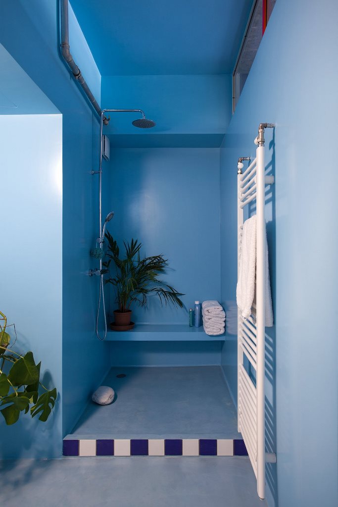 The bathroom is done in light and power blue, with a zoy shower nook and some bright tiles