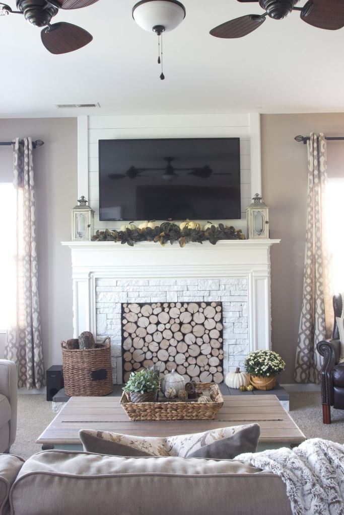 a rustic fireplace clad with white faux fur, a faux mantel and with logs inside for a modern farmhouse living room