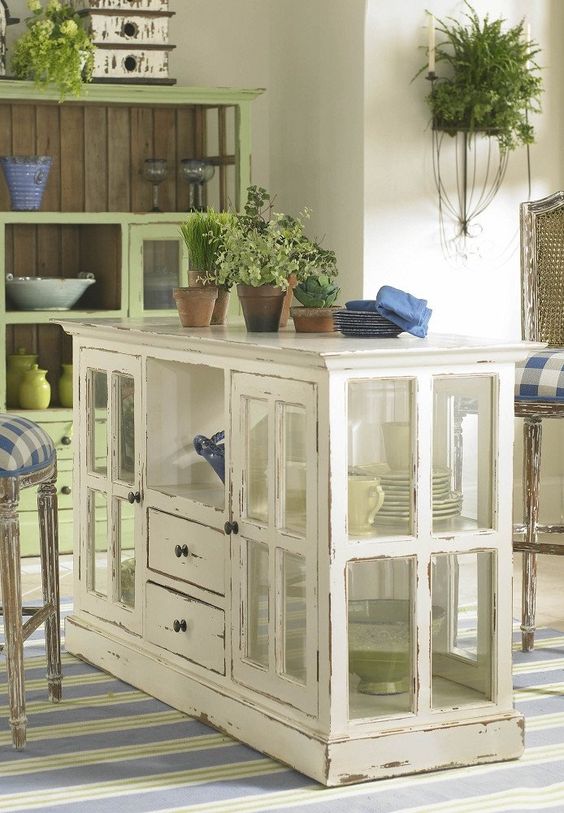 a shabby chic kitchen island made of a cabinet with window frames as glass doors and drawers is a stylish idea