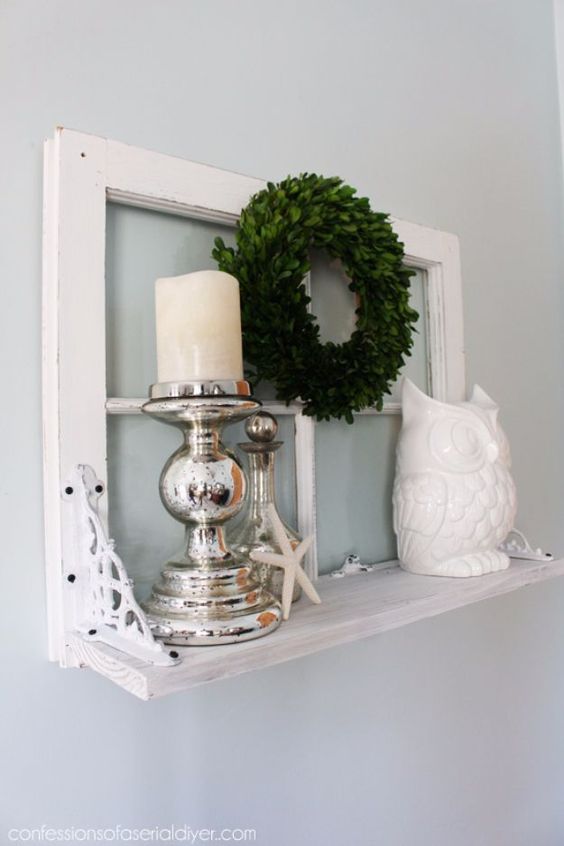 a small shelf with an old window frame as a base, mercury glass candleholders, a greenery wreath, an old is a stylish decoration for a vintage space