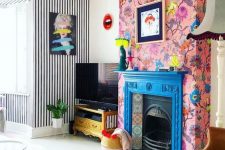 16 a blue fireplace with colorful tiles and pink floral wallpaper around that accent the hearth even more