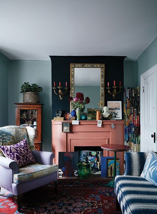 A bright whimsical living room with a salmon pink fireplace and colorful artworks looks unusual and very eye catchy