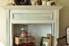 17 a vintage fireplace with vintage suitcases, picture frames, a cloche with greenery and candles on the mantel