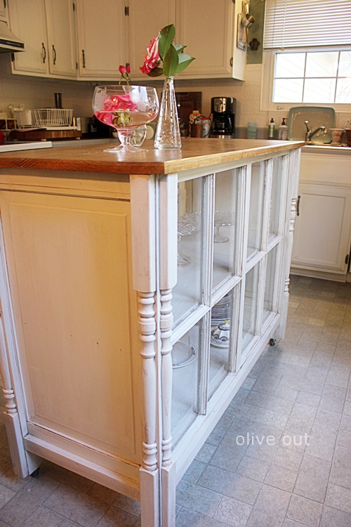 a vintage kitchen island with inner shelves and window frames covering them is a stylish idea with a refined feel