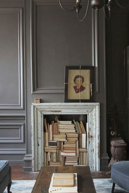 a shabby chic fireplace clad with a refined old picture frame and with lots of books inside is a refined and bold idea