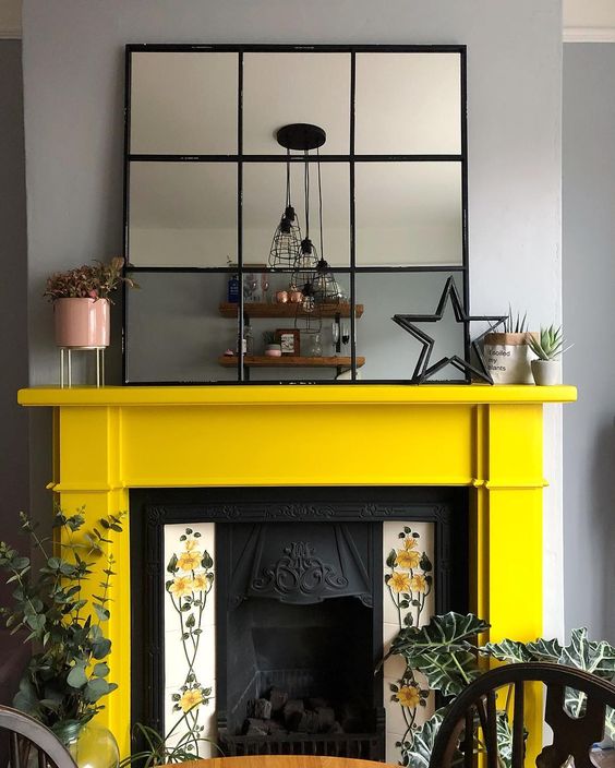 A vintage fireplace with floral tiles on each side and a sunny yellow mantel looks very refined and vintage inspired