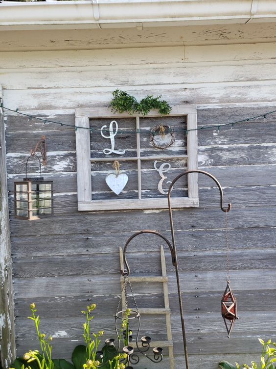 a pretty and easy rustic artwork made of an old window frame, some wooden letters, a wreath and a heart plus greenery can be used indoors and outdoors