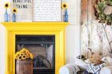 25 a sunny yellow fireplace, a bold blue ottoman and blue bottles with sunflowers to make the space bolder