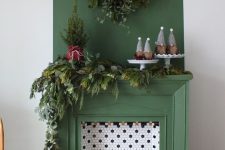 26 a green non-working fireplace with hex tiles and candles inside, with lush evergreens for Christmas