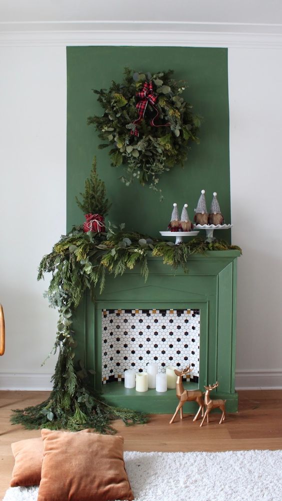 a green non-working fireplace with hex tiles and candles inside, with lush evergreens for Christmas