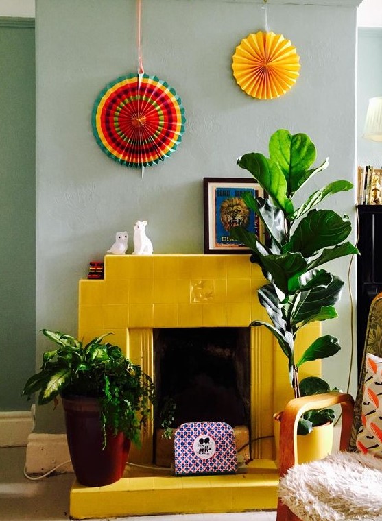 a bold yellow fireplace clad with tiles contrasts the soft and soothing mint color on the wall