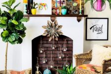 a colorful boho fireplace with candle bubbles inside, candle lanterns, potted plants, a colorful tapestry and bright planters