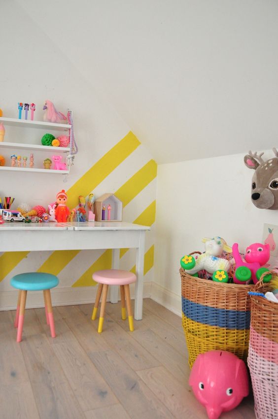 a colorful kids' playroom accented with a yellow and white striped wall and lots of bold toys