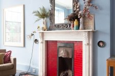 a dusty blue living room with a fireplace clad with bold red tiles is a cool space that looks chic and contrasting