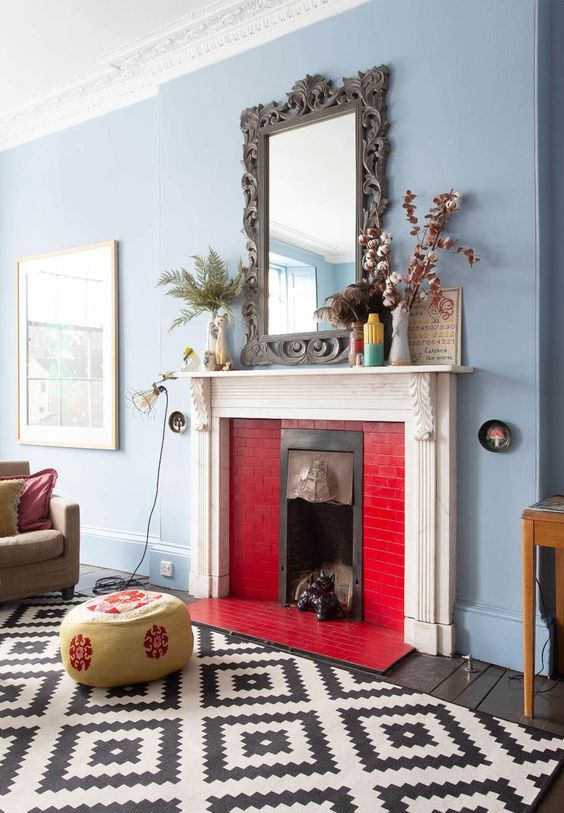 a dusty blue living room with a fireplace clad with bold red tiles is a cool space that looks chic and contrasting