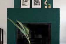 a forest green brick fireplace with some decor on the mantel, a black coffee table and a cool coral vase with leaves