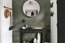 a modern entryway with a green paneled wall, a black console, some railings and planters on the wall