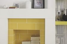 a modern sleek fireplace clad with yellow tiles, with books stored inside is a real centerpiece in a modern living room