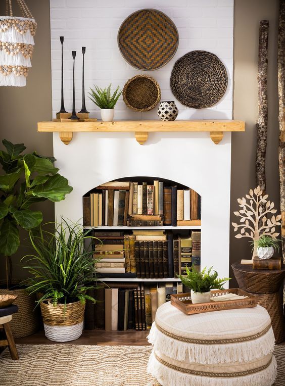A non working fireplace as a bookcase, with lots of books and lights, with boho baskets and candles on the mantel
