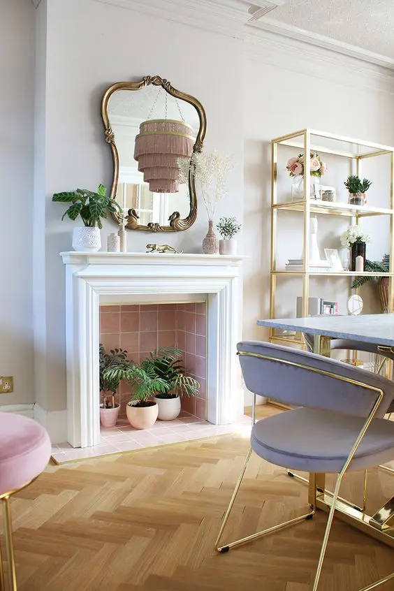 A non working fireplace clad with pink tiles, with potted plants inside is a cool addition to a bright space