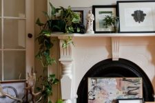a non-working fireplace to display beautiful art, artwork arrangement on the mantel, potted greenery