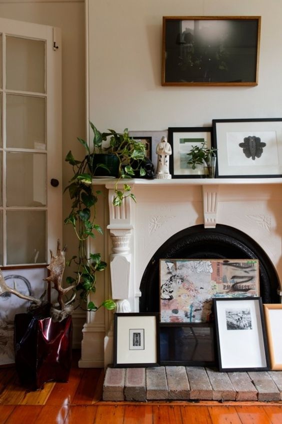 A non working fireplace to display beautiful art, artwork arrangement on the mantel, potted greenery