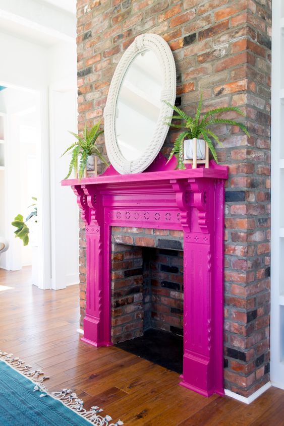 A non working fireplace with a fuchsia mantel, potted plants and a mirror in a rope frame is a cool idea