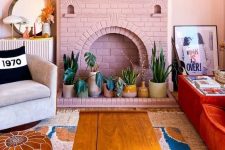 a pink brick fireplace with potted plants instead of fire is a cool and fresh decor idea for a boho space