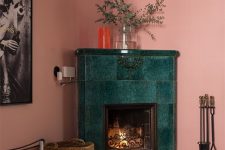 a pink living room with a green tile fireplace, a basket and a stand with tools is an elegant and chic space
