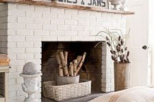 a rustic white brick fireplace with a basket, a bucket with branches, vintage urns and moss, pinecones and branches