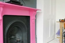 a vintage black metal fireplace and a hot pink mantel over it is a bold and chic touch of color with a playful feel