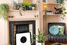 a vintage non-working fireplace with an artwork, candle lanterns and a potted plant next to it