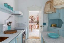02 The kitchen is done with beautiful blue cabinets, white marble countertops and backsplashes and rattan pendant lamps