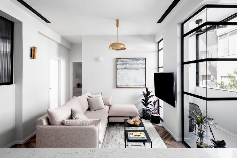 The living room features a blush sectional, a statement artwork, brass touches and an entrance to the balcony