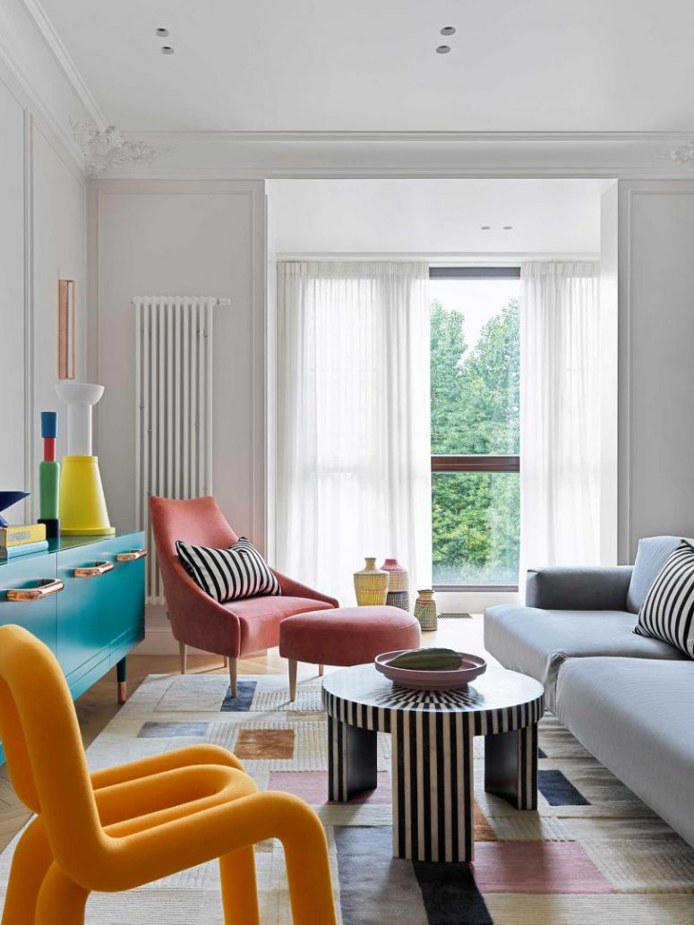 The living room features colorful furniture and objects, striped accents and bold accessories