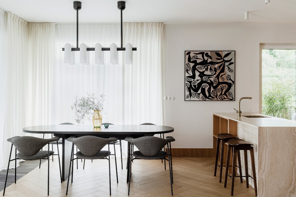 The kitchen and dining space are united into one layout, with chic furniture, quirky art and bold lamps