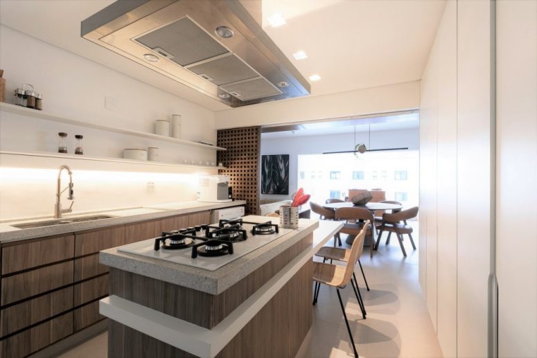 The kitchen shows off wooden cabinets and white stone countertops, with built-in lights and sliding panels that can be opened or closed
