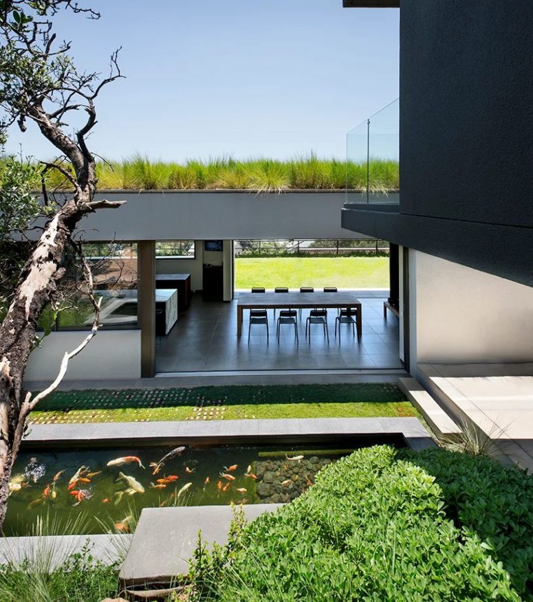 The living areas can be opened to outdoors, and there you can see a green lawn and a pond with real fish