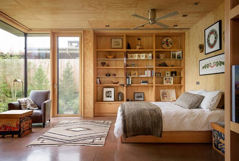 The bedroom has several glazed walls and is all done of wood and plywood plus boho textiles